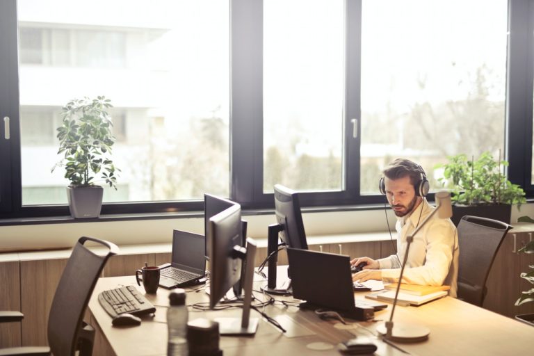 a person sitting at a desk with a laptop and a computer